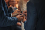 A couple exchanging rings in a cozy indoor space with soft natural light.