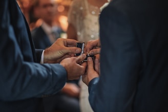 A smiling couple exchanging rings in a traditional Muslim wedding ceremony.