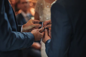 A couple exchanging rings in a cozy indoor space with soft natural light.