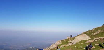 Field geologists working together on a rocky hillside under clear skies.