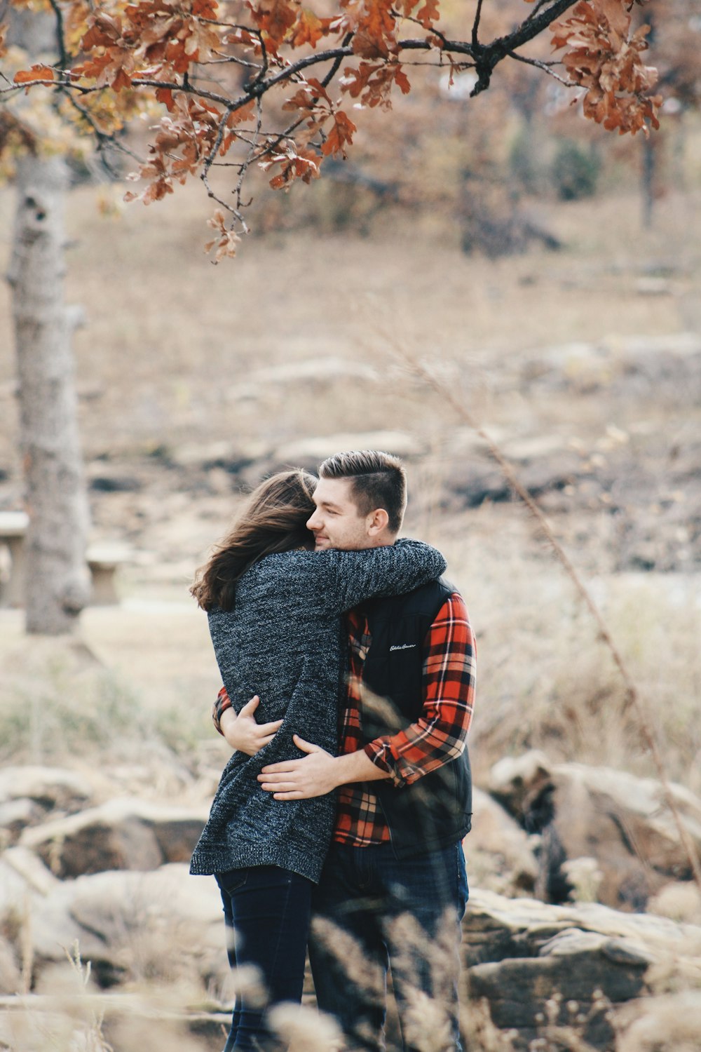 a man and a woman hugging under a tree