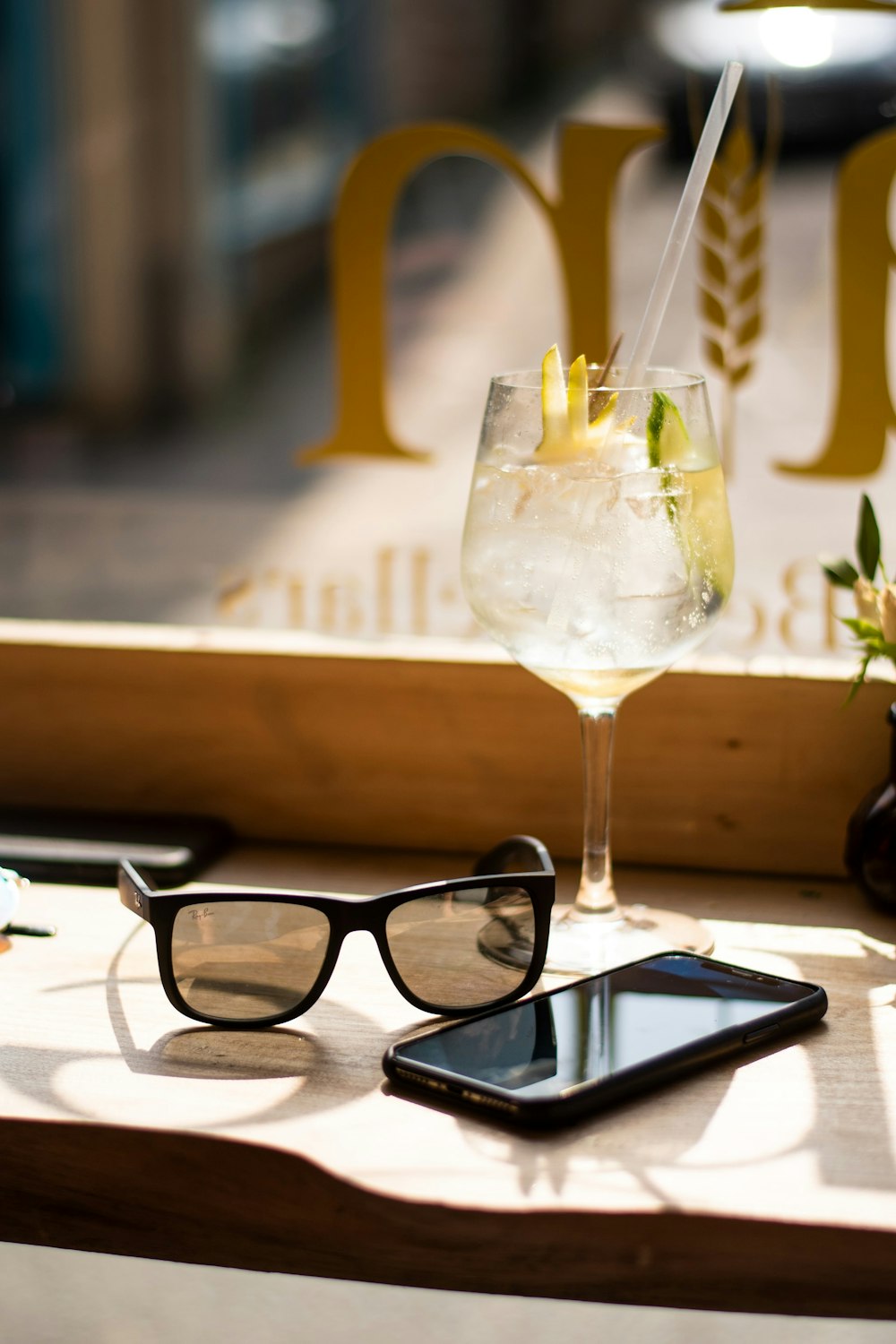 Smartphone, occhiali da sole Wayfarer e bicchiere di vino su vassoio
