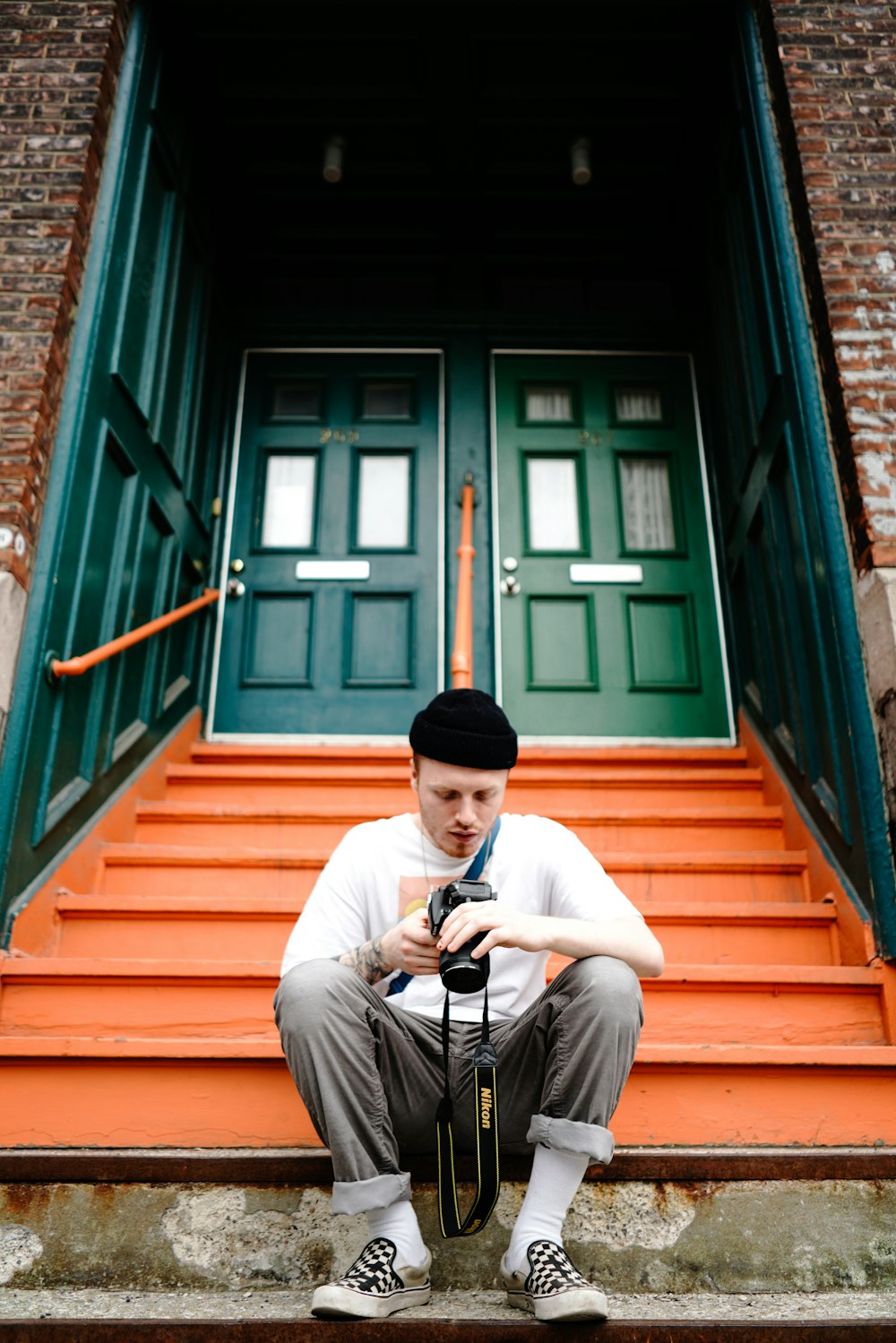 homem sentado na frente da escada enquanto segura a câmera DSLR