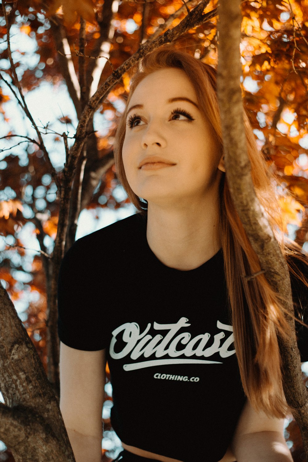 woman wearing black crew-neck shirt sitting on tree