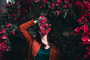 woman holding flower standing near flowers