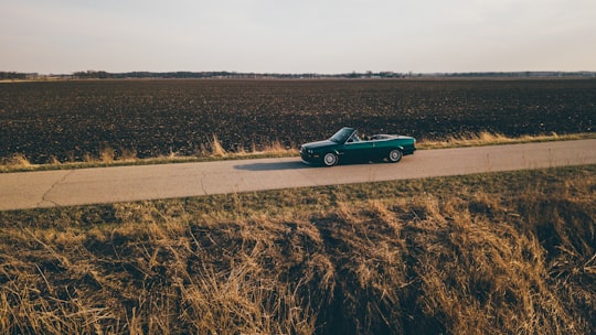 convertible coupe on road between grass field in Madison United States