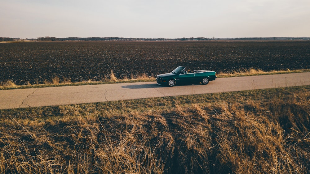 convertible coupe on road between grass field