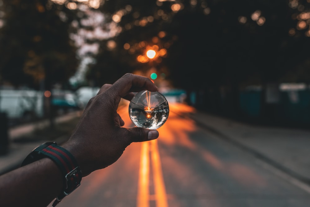 person holding snow globe under sunset