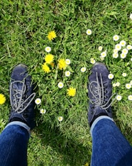 Close-up of hiking boots stepping on a rugged trail with wildflowers