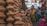 A bustling market scene where several women are gathered around a variety of clay pots and earthenware. The pots are stacked in unique shapes, displaying a rich cultural craft. The women are dressed in colorful traditional attire, engaging in conversation or examining the pottery.