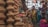 A bustling market scene where several women are gathered around a variety of clay pots and earthenware. The pots are stacked in unique shapes, displaying a rich cultural craft. The women are dressed in colorful traditional attire, engaging in conversation or examining the pottery.