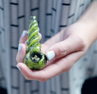 selective focus photography of person holding spoon pipe with kush