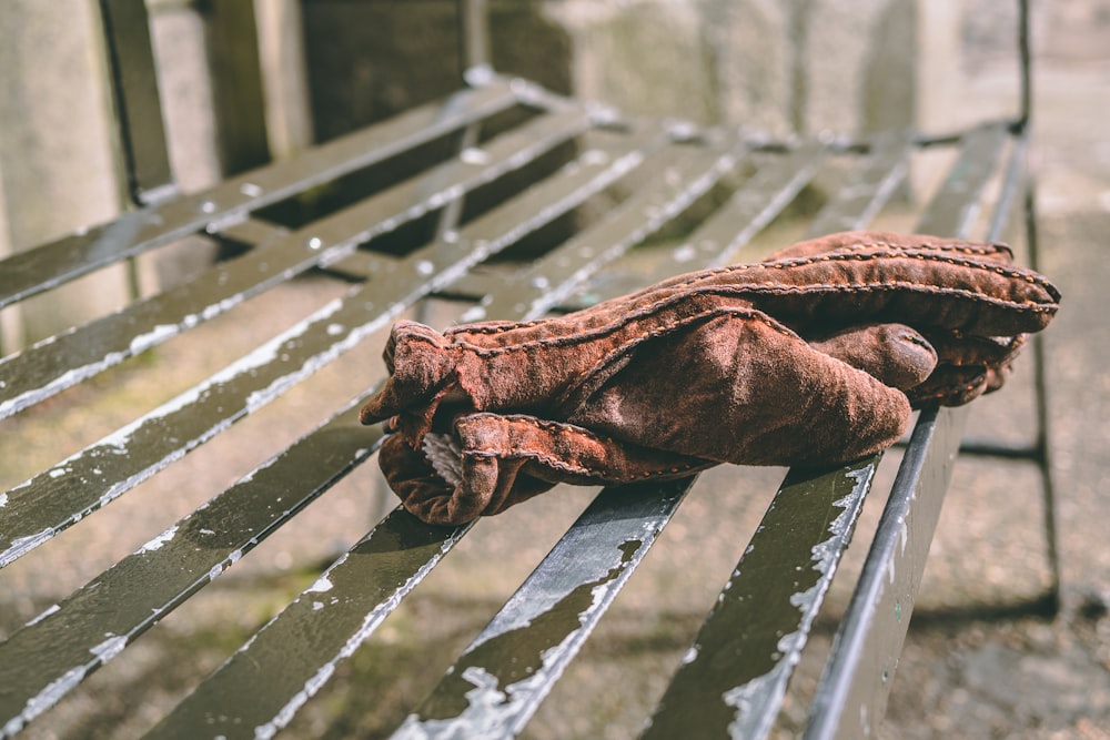 pair of brown mittens on black metal bench