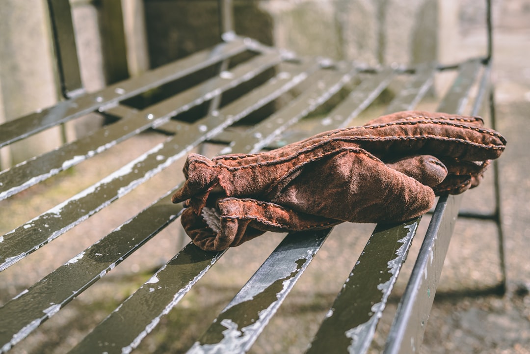 pair of brown mittens on black metal bench,
