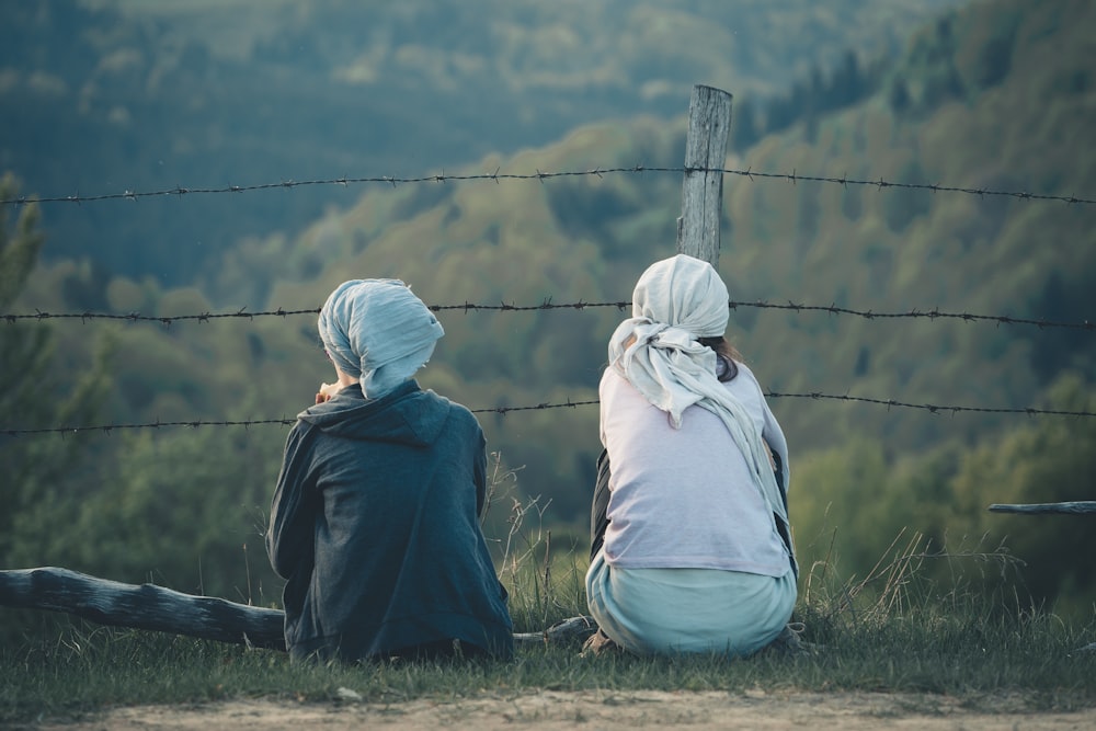 two people sitting on green grasses