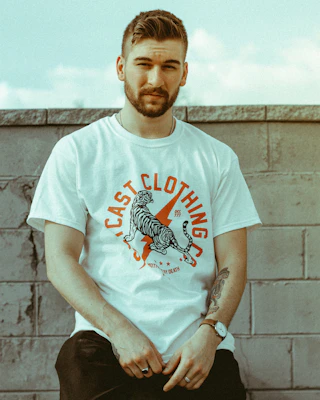 Charcoal-toned oversized tee featuring bold, rebellious artwork displayed on a minimalist concrete wall.