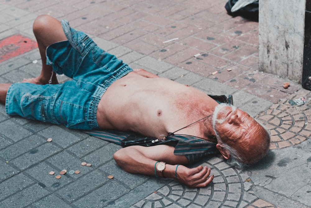 topless man lying on brick pavement