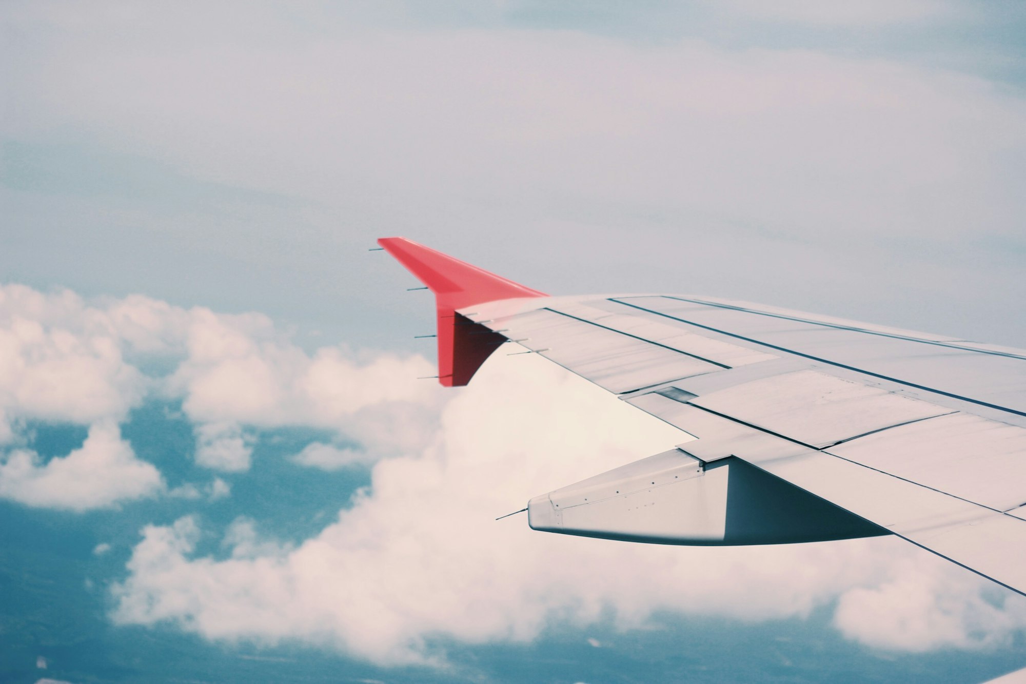 The left wing of an airplane over a backdrop of sky and clouds