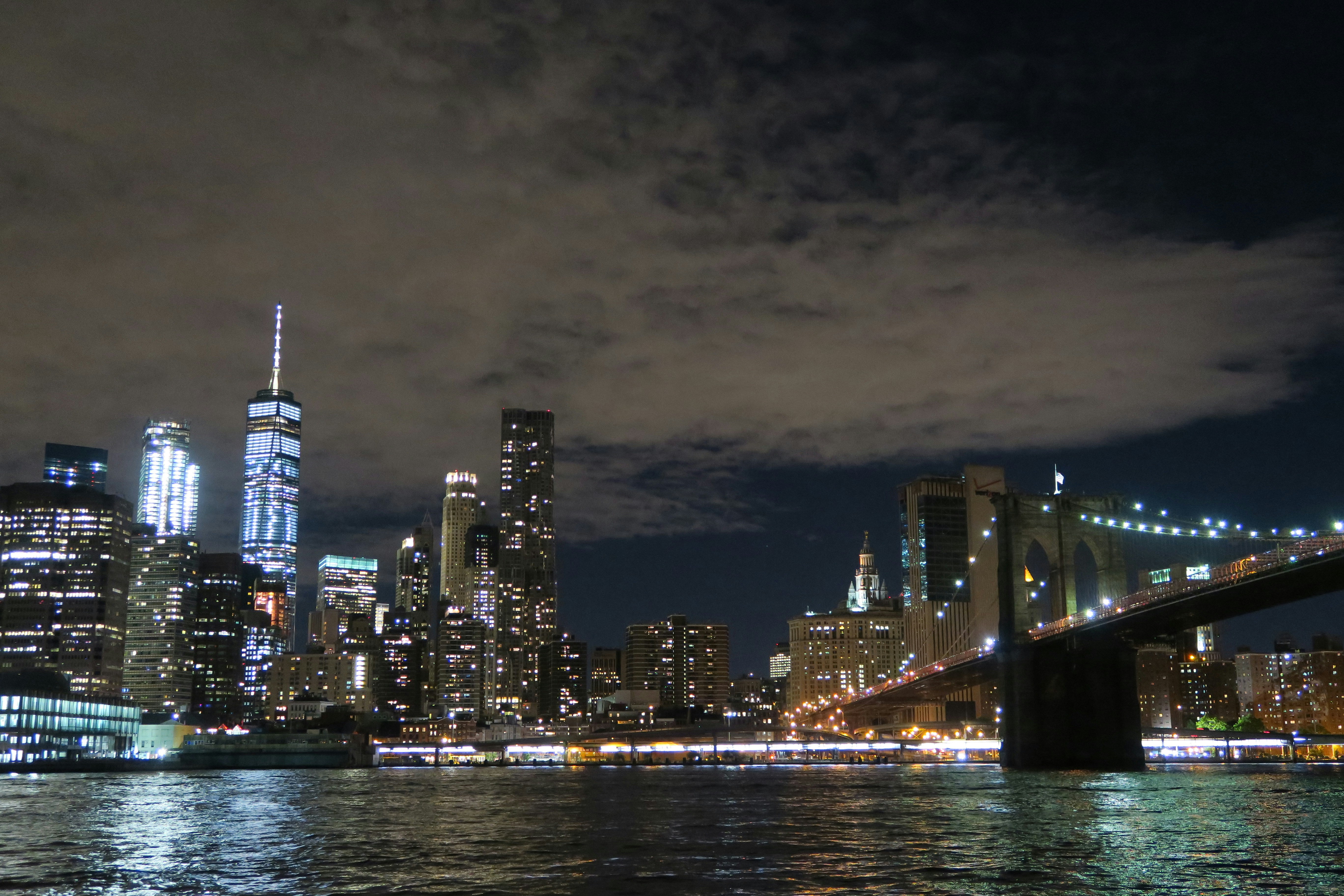 Skyline di New York di notte con luci brillanti e Brooklyn Bridge illuminato