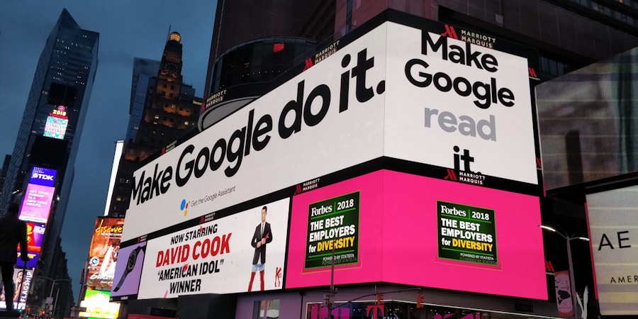 A bustling urban setting with large digital billboards displaying colorful advertisements. Prominent ads include 'Make Google do it' and 'American Idol Winner David Cook'. Bright neon colors and giant screens dominate the scene, hinting at a lively nightlife area.