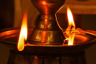 A close-up of a beautifully crafted brass kuthu vilakku glowing softly in warm light.