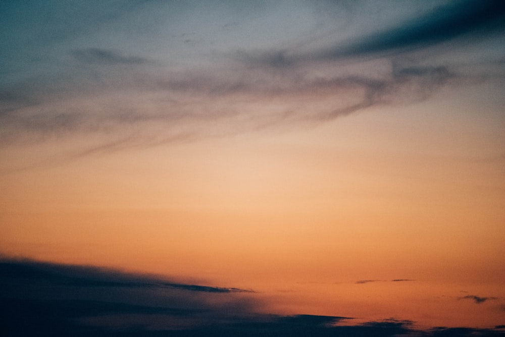 a plane flying in the sky at sunset