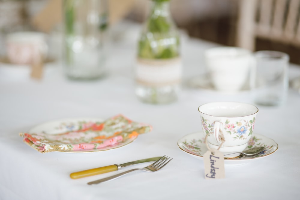 Vajilla blanca y plateada encima de mesa de madera blanca