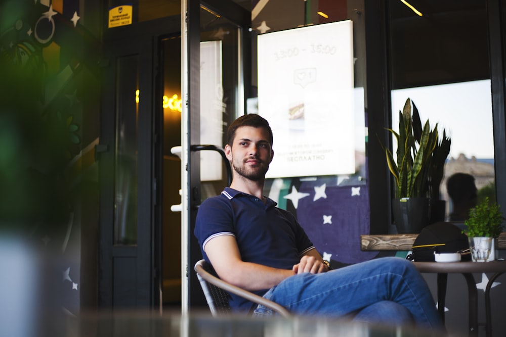 man sitting on chair in front of table near clear glass