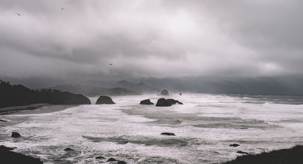 rock formations between sea under gray sky