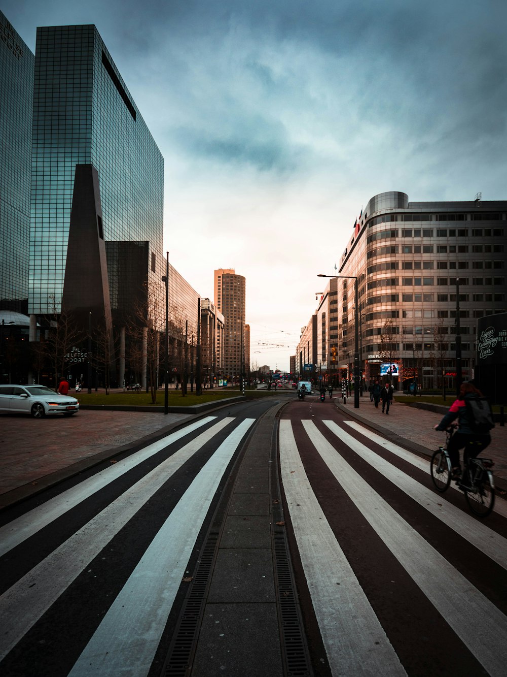 people biking and walking on road near buildings during daytime