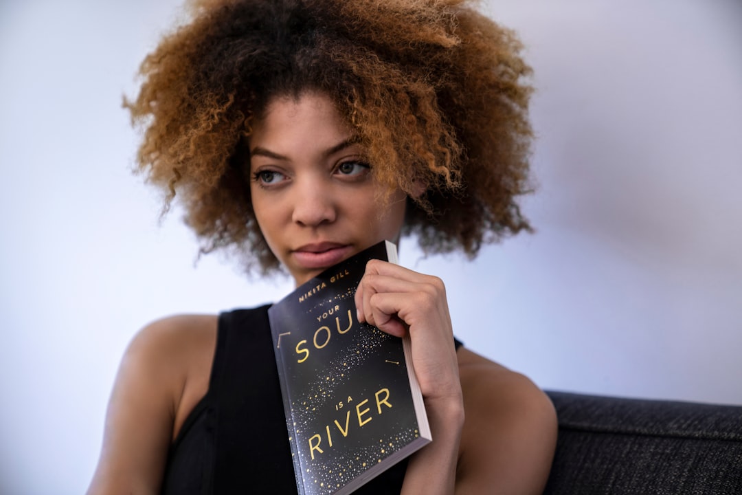 woman holding book leaned on chin