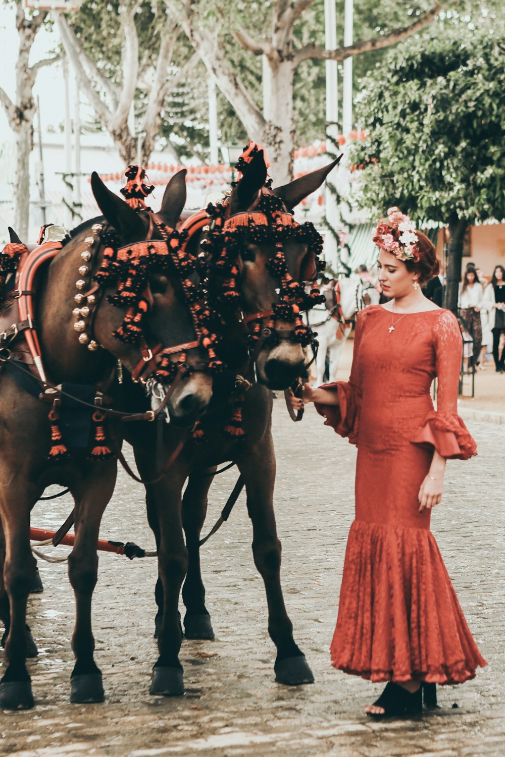 mulher ao lado de cavalos marrons durante o dia