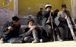 A circle of boys and mentors sitting on sand-colored blankets, engaged in respectful conversation.