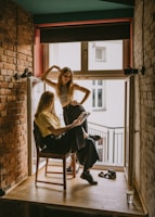 woman standing beside another woman sitting on chair