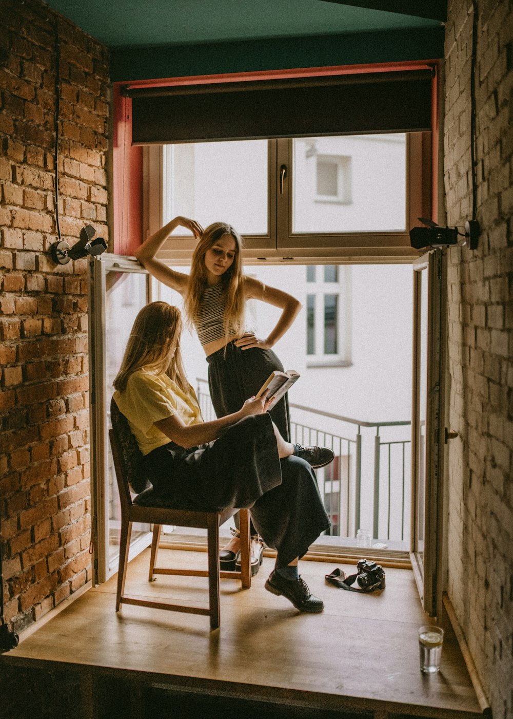 woman standing beside another woman sitting on chair