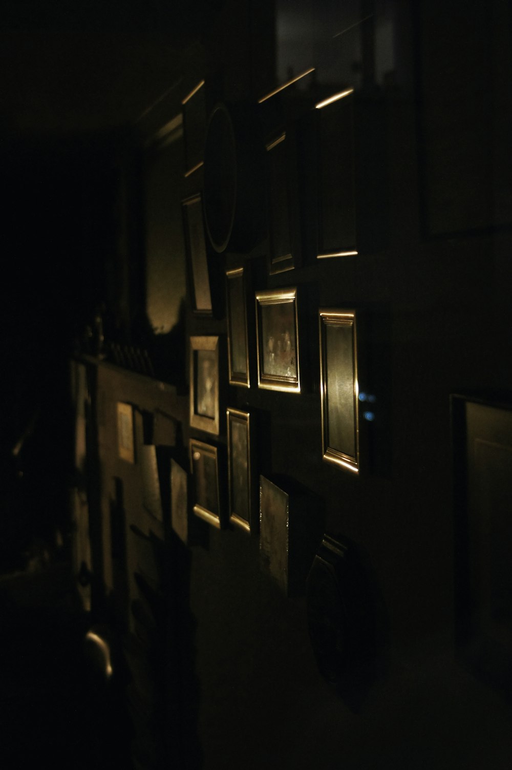 um quarto escuro com um monte de quadros emoldurados na parede