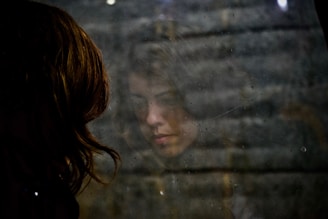 Mulher triste pensativa observando seu reflexo no vidro