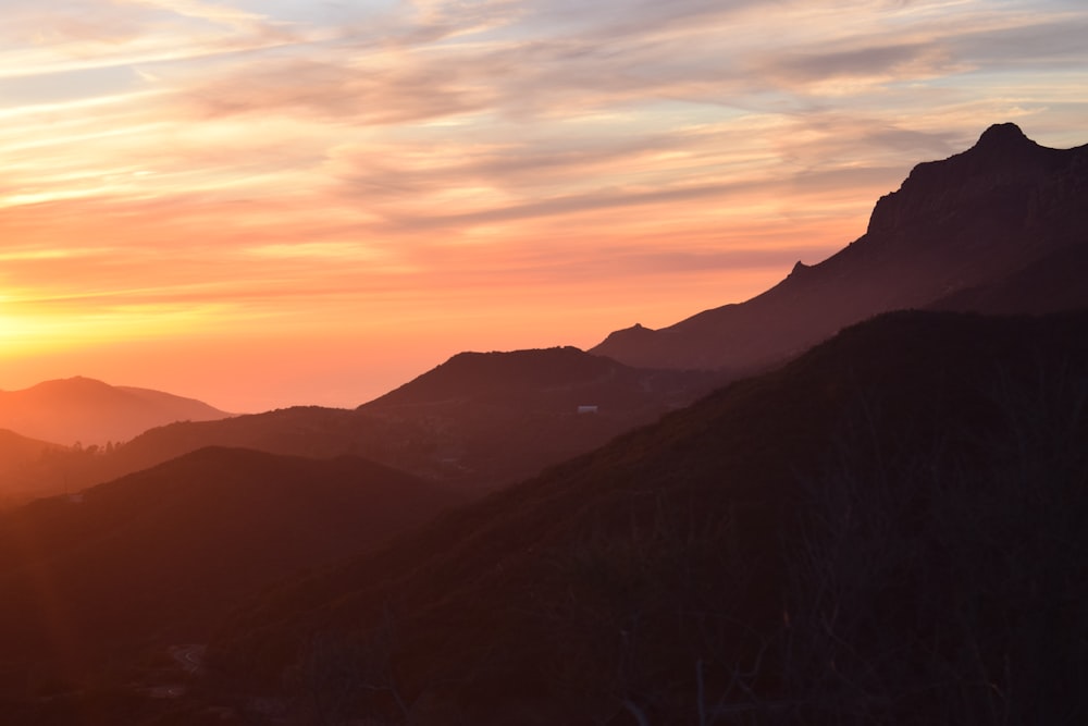 silhouette of mountain under cloudy sky during golden hour