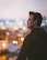 Headshot of a thoughtful man wearing glasses, with a futuristic cityscape blurred in the background.