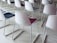 Rows of modern chairs with white plastic backs and colored seats arranged neatly. The floor is made of light-colored tiles, creating a clean and organized atmosphere.
