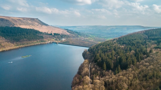 aerial view of trees field beside blue sea under white cloudy sky in Ladybower Reservoir United Kingdom