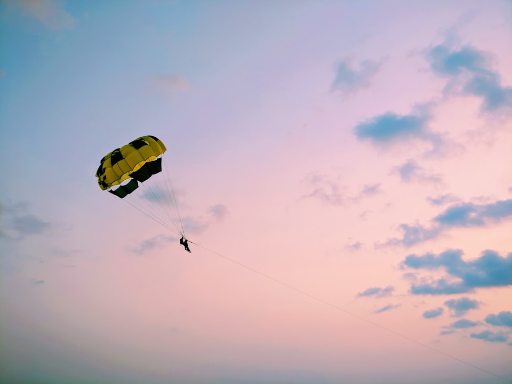 a person is parasailing in the sky at sunset