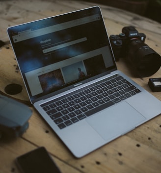 silver MacBook Air and SLR camera on table