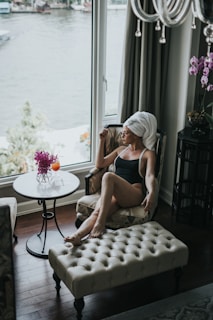 woman wearing one-piece swimsuit sitting on chair while looking outside
