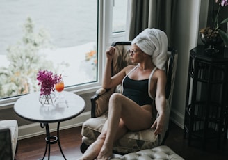 woman wearing one-piece swimsuit sitting on chair while looking outside