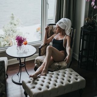 woman wearing one-piece swimsuit sitting on chair while looking outside