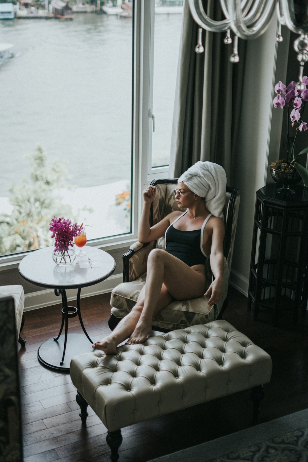 woman wearing one-piece swimsuit sitting on chair while looking outside