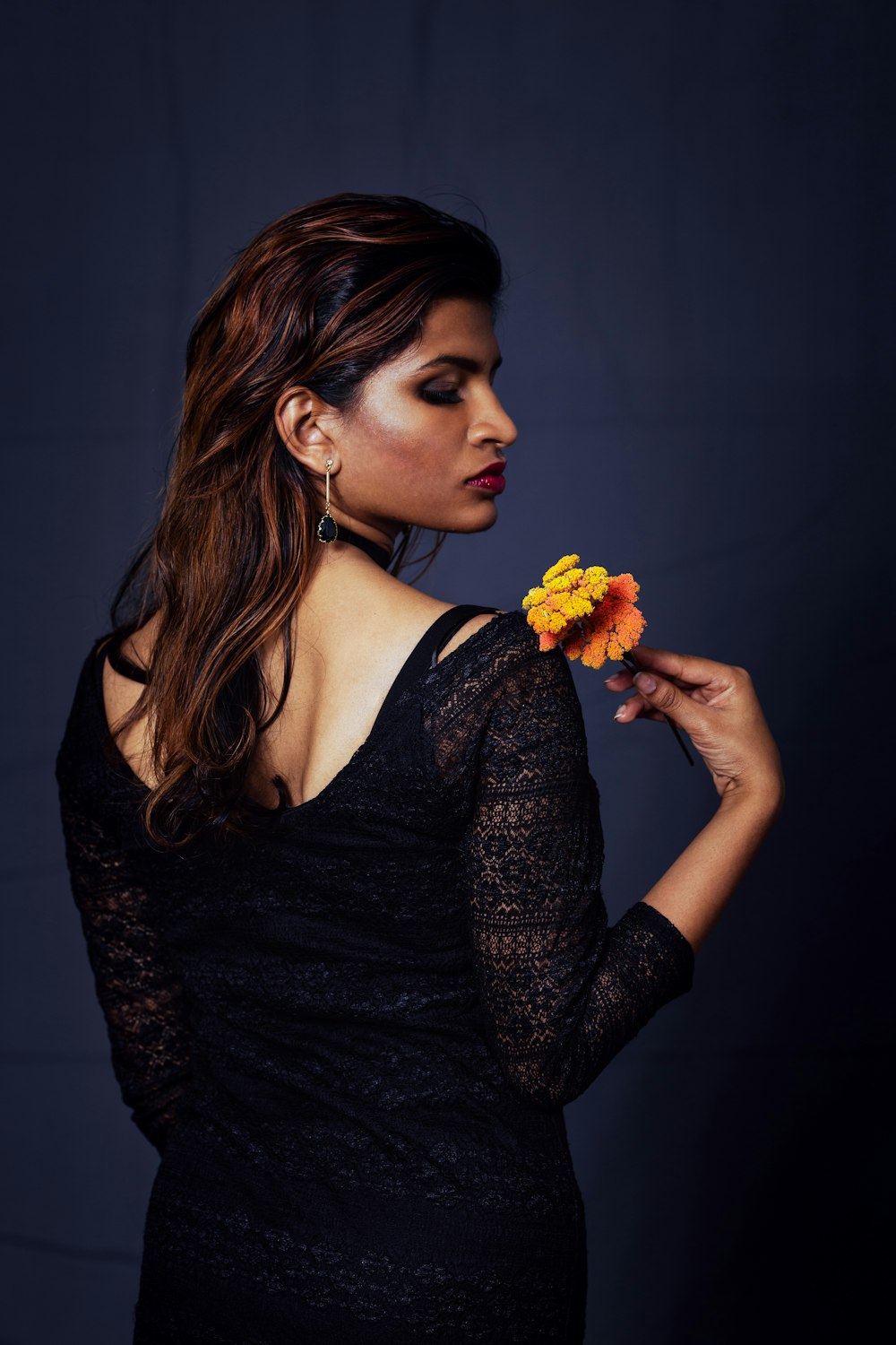 woman wearing black long-sleeved dress holding flower