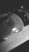 Close-up of a vintage microphone with silver tones reflecting soft studio lights.