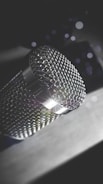 Close-up of a vintage microphone with soft blue lighting reflecting off its chrome surface.